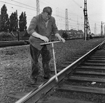 153398 Afbeelding van een wegwerker van de N.S. tijdens het aandraaien van een kraagbout op het emplacement van het ...